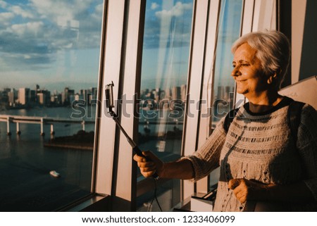
Beautiful aerial view of Tokyo Bay from the Odaiba district. Middle-aged woman taking pictures with her smartphone. Travel Photography.