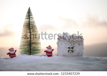 Christmas and New Year miniature house in the snow in the sunlight. Little toy house on snow with tree. Festive background. Christmas decorations. Holiday and celebration concept.