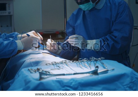 surgical instrument lying on table while group of surgeon work in operation room at hospital, emergency case, surgery, medical technology, health care cancer and disease treatment concept