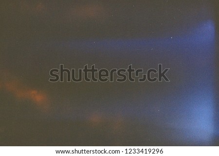 Dark analog film frame like a night sky, with grain, orange blue light leak. Abstract old film background

