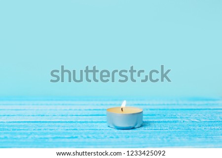Small candle with dark blue background. One candle on the table