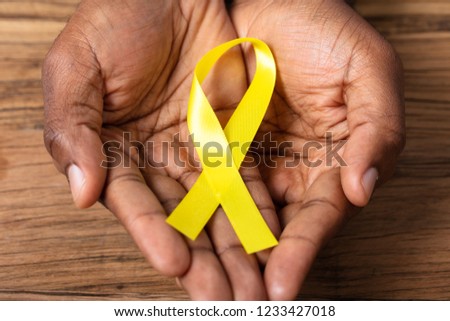 Person's Hand Holding Ribbon To Support Childhood And Bladder Cancer