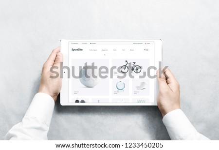 Hands holding tablet with sport webstore mock up on screen, isolated. Training web page interface mockup. Internet website template. Web store screen layout for computer display.