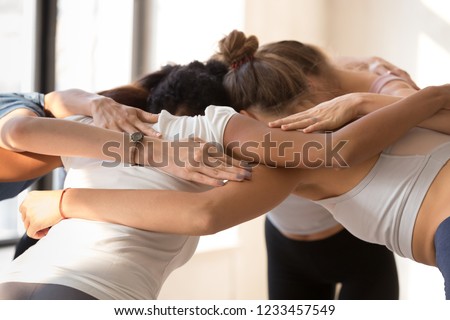 Close up of team diverse girls embracing standing in circle having motivational pep talk before match indoors. Multi-ethnic females congratulating each other after sports training hugging feels happy Royalty-Free Stock Photo #1233457549