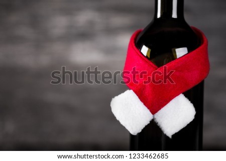 Wine bottle decarated with santa claus hat and scarf on wooden background, nobody