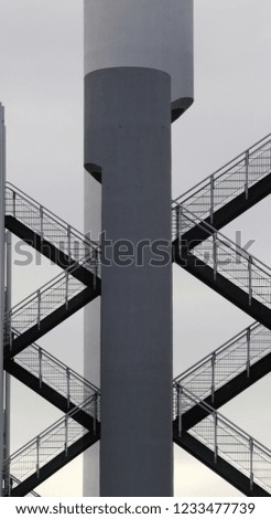 Reworked photo of industrial building fragment featuring metal staircases and pillars. Abstract black and white image on the subject of modern architecture, industry and technology.