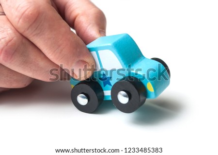 closeup of blue miniature wooden car in hand on white background - concept police