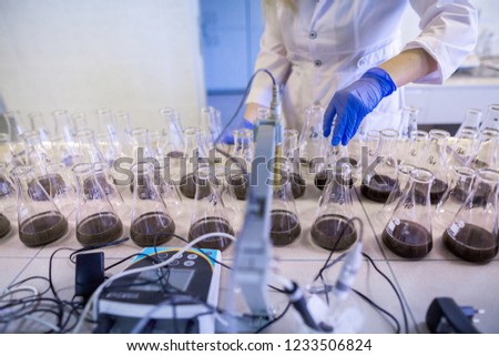 Hands of the scientist in laboratory shake a glass flasks with dissolved samples of the soil. Agrochemical examination of soil to more efficient use resources and optimize the use of fertilizers.