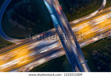 Highway junction seen from above at night with light trails of passing cars