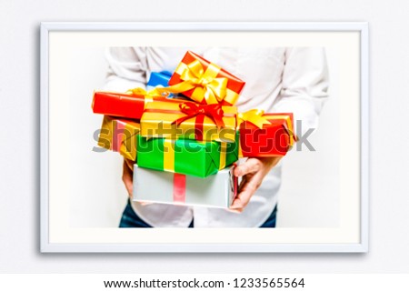 Male hands holding a gift boxes. Presents wrapped with ribbon and bow. Christmas or birthday colored packages. Man in white shirt. Wall frame poster with gift present box photo. Mockup template.