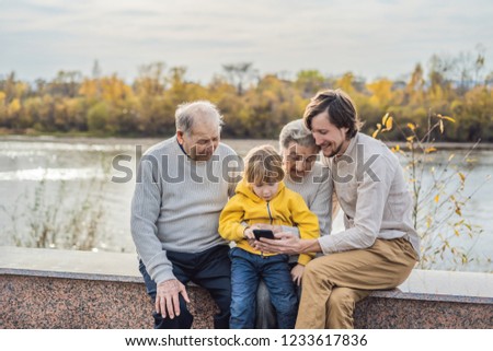 The boy shows the photo on the phone to his grandparents