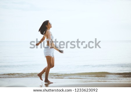 Summer vacation concept, Travel asian woman with white bikini and straw hat walking on sea beach at Chanthaburi, Thailand