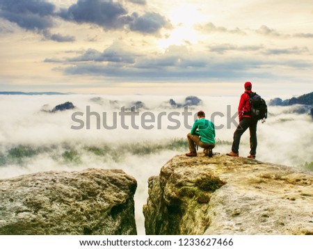 Photographer check weather condition. Freelancer stay with camera on cliff and thinking. Dreamy fogy landscape blue misty sunrise