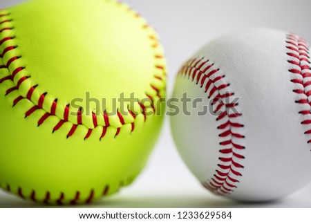 A yellow softball and white baseball on a white background shot with a macro lens