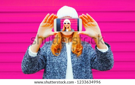 Happy smiling woman taking selfie close-up by smartphone having fun on colorful wall background