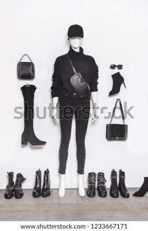 A set of black fashionable clothes on full mannequin and accessories on a gray background


