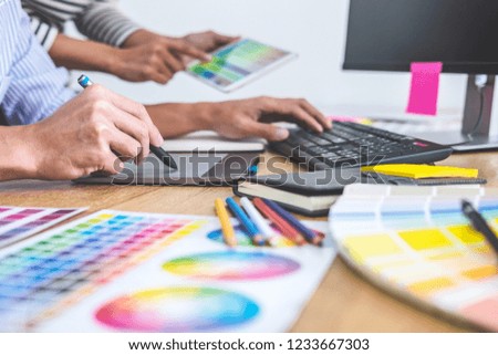 Two colleagues creative graphic designer working on color selection and drawing on graphics tablet at workplace, Color swatch samples chart for selection coloring.