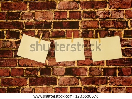 Photos hung on rope with wooden pegs template with blank photo paper to insert your photos. Vintage red brick wall in background. 