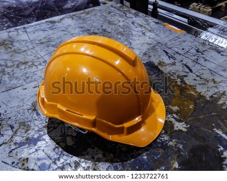 orange safety helmet and bright orange suit for safety sign on rusty metal panel