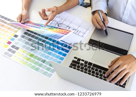 Team of colleague graphic designer drawing and retouching image on graphics tablet and choose color swatch samples for selection on laptop computer.