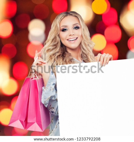 Woman with blonde curly hair holding pink shopping bag and white empty paper board with copy space