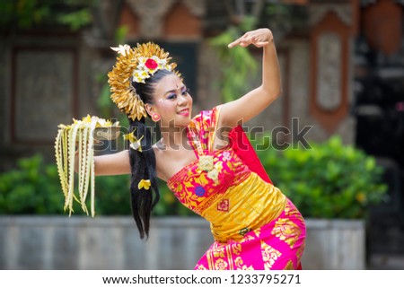 Picture of a beautiful female dancer wearing traditional dress costume while doing Pendet dances in the temple