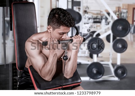 Picture of a young man exercising with a weight machine in the gym center