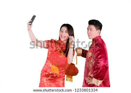 Young Asian couple holding Chinese new year lantern while taking a photo together in the studio