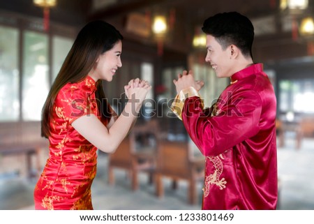 Picture of happy Chinese couple congratulating each other while standing at home