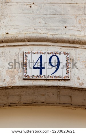 House number forty-six 46 painted on white ceramic tile in blue, gold and yellow from France