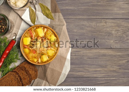 Sauerkraut soup in bowl with black pepper and bay leaves on the side. Photographed overhead on rustic wood.Copy space.
