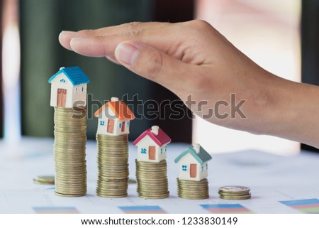 Hand protection, house model on top of stack of money as growth of mortgage credit, Concept of property management. Invesment and Risk Management.