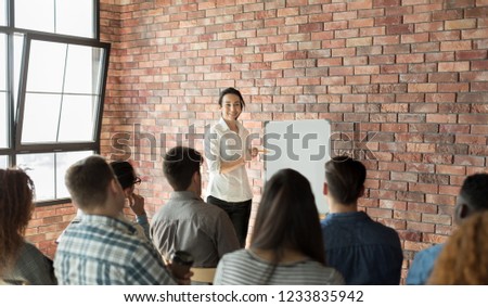 Businesswoman speaking at crowdsourcing seminar at loft office, pointing at whiteboard, copy space Royalty-Free Stock Photo #1233835942