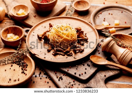 italian spaghetti pasta with mushrooms chanterelles and parmesan rash, seasoned with saffron and pepper spices on a wooden table.