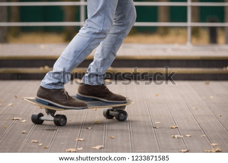 Closeup of a men's feet on a skateboard. Fashionably dressed young man riding a skateboard. View of a person riding on his skate. The concept of sport and active life