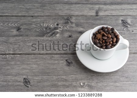 Cup of coffee beans on wooden background with selective focus and crop fragment