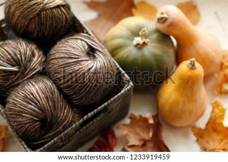 Autumn lifestyle home decor - wooden basket with brown wool yarn, needles, organic pumpkin and autumn dry leaves 
on an windowsill. Christmas, thanksgiving holidays at home, calmness closeup