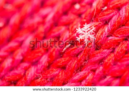 snowflake on the knitted wool red mitten. close up