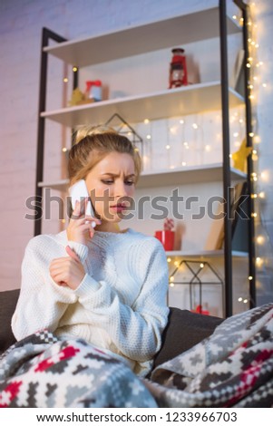 upset young blonde woman talking on smartphone at christmas time 