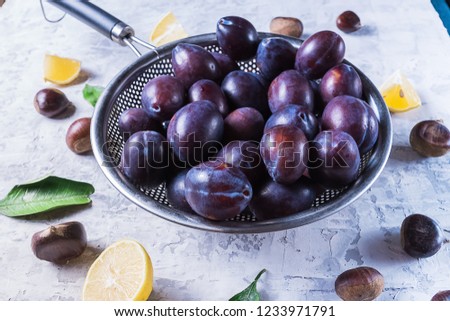 Ripe juicy plums on a plate, on old blue wooden table.