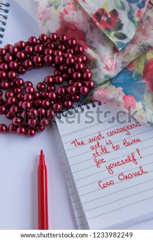 Coco Chanel quotes written on a block note, pearl accessories and  and silky flower shirt ,inspiration phrase "The most courageous act is still to think for yourself"