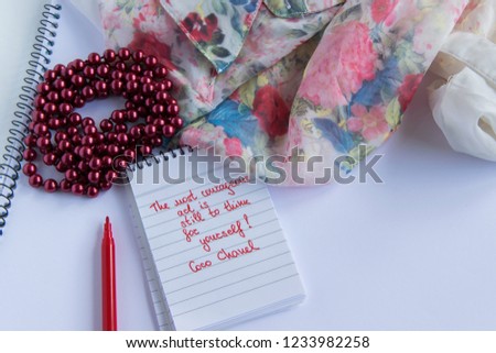 Coco Chanel quotes written on a block note, pearl accessories and  and silky flower shirt ,inspiration phrase "The most courageous act is still to think for yourself"