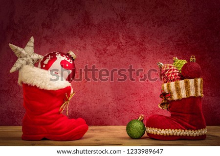 Two red boots of Santa Claus with poinsettia and five Christmas balls as a Christmas decoration