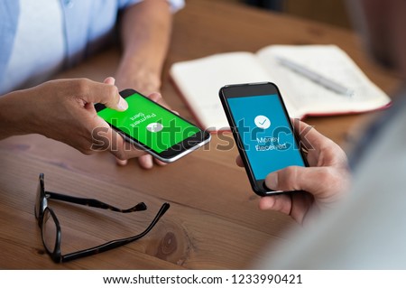 Closeup hands holding mobile phone with application for send and receive money. Man and woman holding smartphone and making payment transaction. Smart phone screen displaying payment sent. Royalty-Free Stock Photo #1233990421