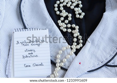 Coco Chanel quotes written on a block note, pearl accessories and a classy jacket ,inspiration phrase "A girl should be two things: classy and fabulous"