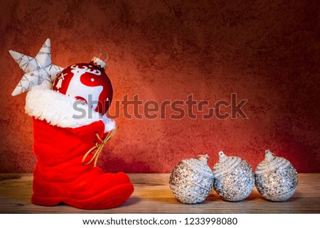 A red boot of Santa Claus with poinsettia and four Christmas balls as a Christmas decoration