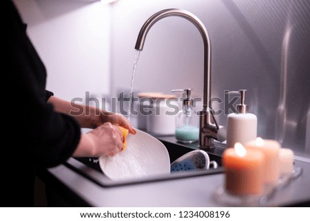 Young woman washing dishes at home.