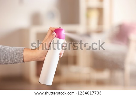 Woman spraying air freshener at home Royalty-Free Stock Photo #1234017733