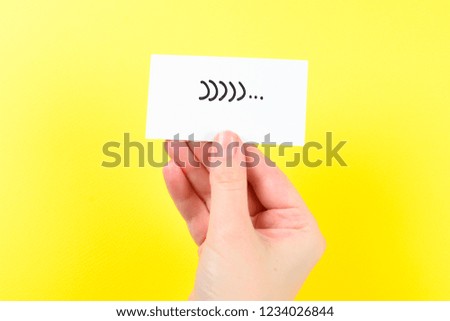 Smile text on a card in woman hand  on a yellow background.