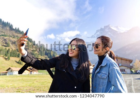 Selfie lifestyle portrait of young best friend girls having fun together at kandersteg, Switzerland. Travel concept,happy girls make picture together and having fun, make funny faces on camera.